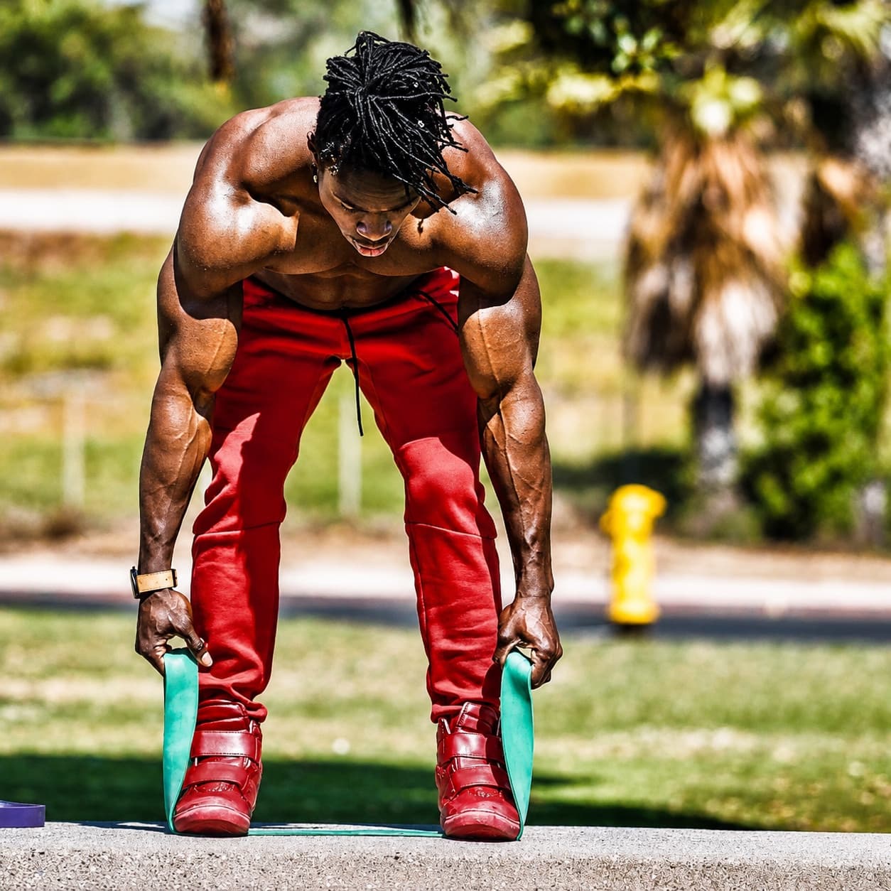 Alseny Sylla gripping a resistance band under his feet during an outdoor training session