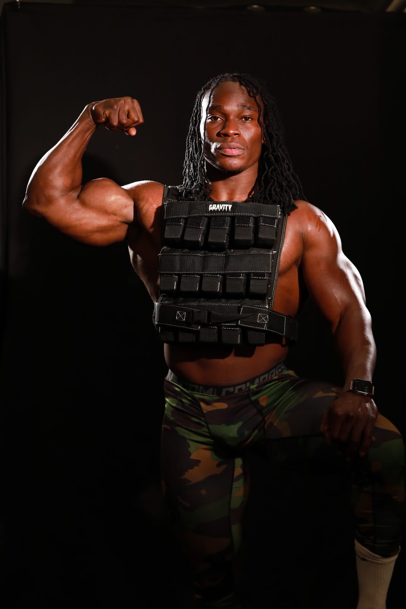 Alseny Sylla flexing one arm while wearing a weighted training vest